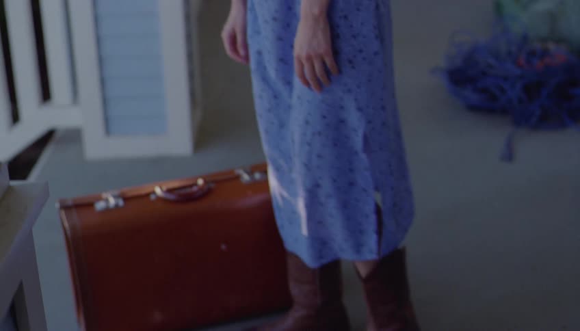 Woman leaving a suitcase in the backyard of a house