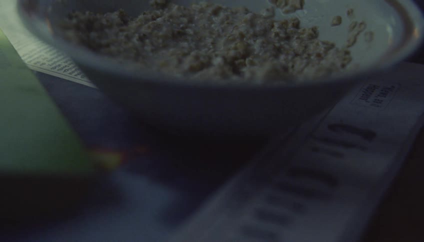 A metal spoon scoops a small amount of oatmeal from a glass bowl