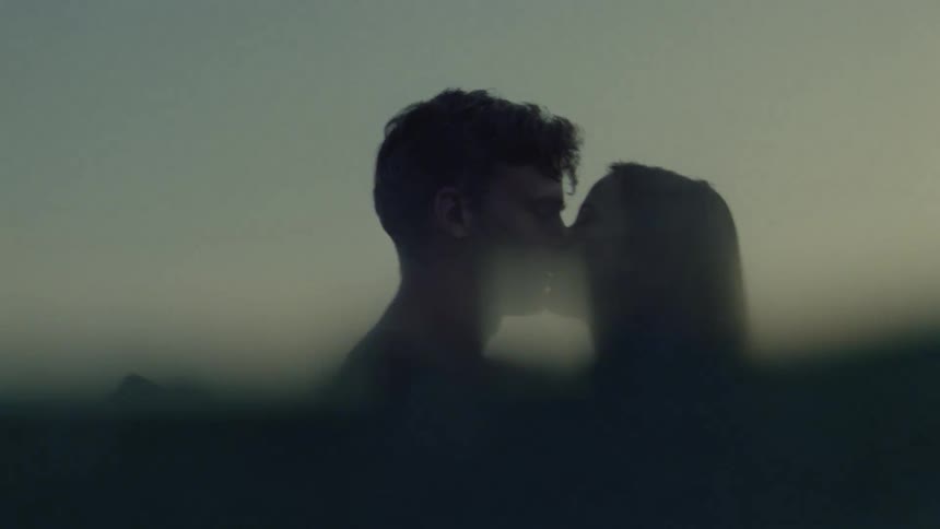 Couple kissing in silhouette at sea at dusk