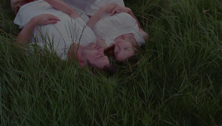 Man and a woman lie on the grass together and talk