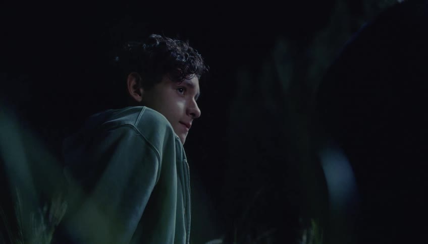 Boy in profile at night wearing a hoodie under low light