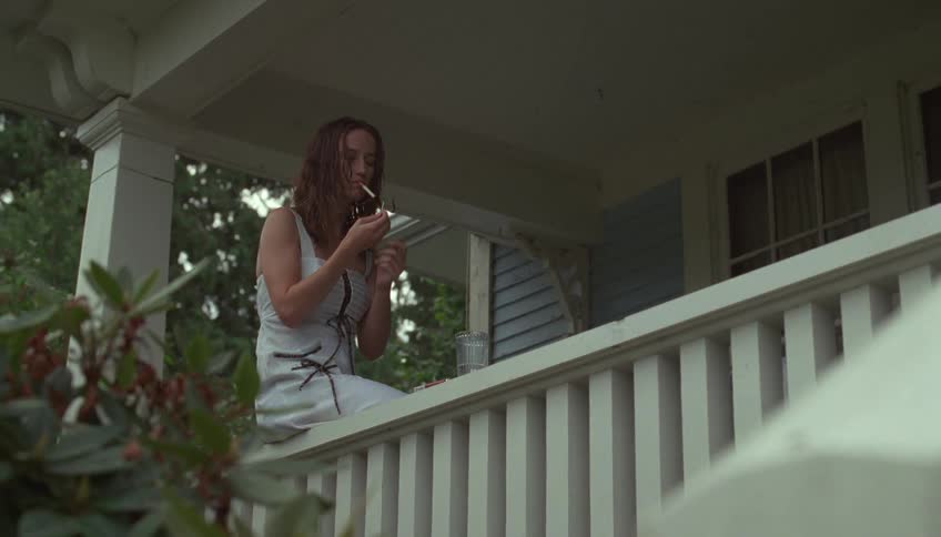 The woman is smoking on the porch