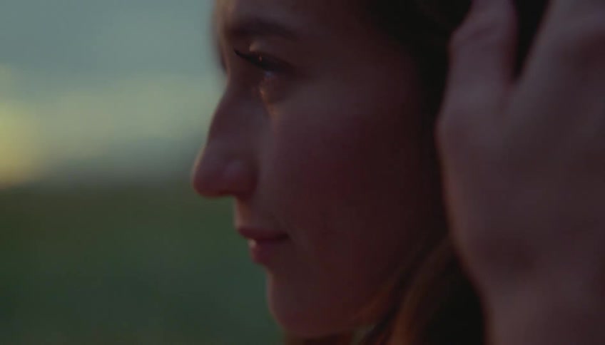 Couple faces each other in profile in an outdoor setting at dusk