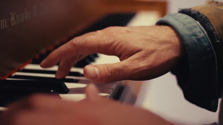 A closeup of a persons hand gently pressing piano keys captures the quiet focus and intimacy of playing music