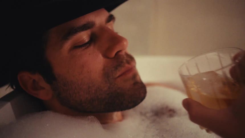 The man has a drink in the tub