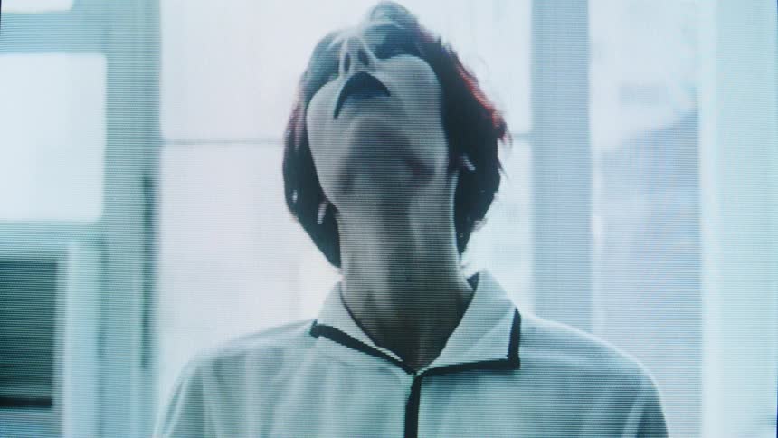 A dramatically made up person in white clothing performs expressive hand movements