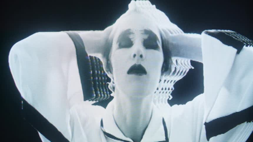 Woman with dark makeup touches her face