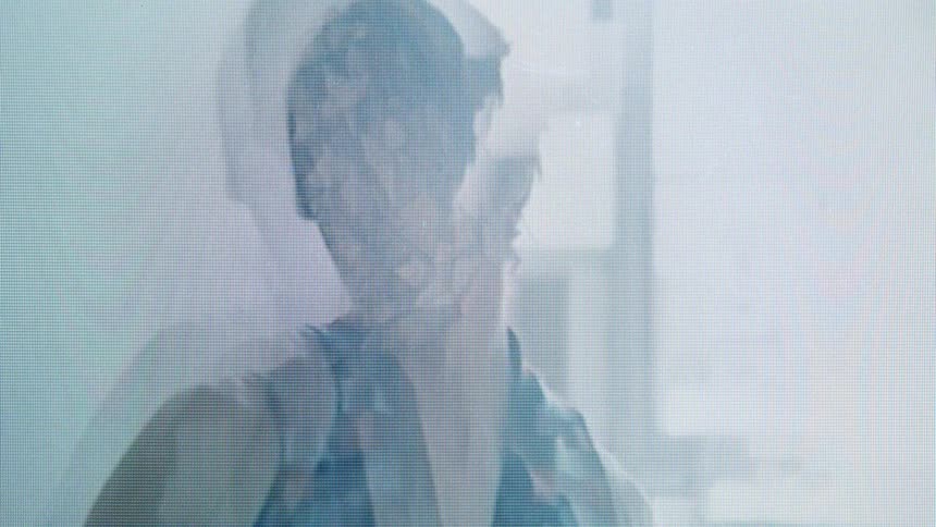 Woman wears a translucent facial mask in an indoor setting with diffused lighting