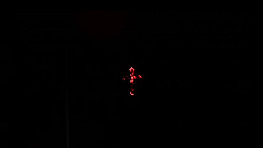 Red illuminated cross stands out against a completely dark background