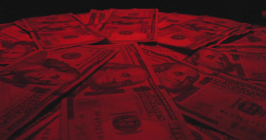 Us dollar bills spread under intense red lighting