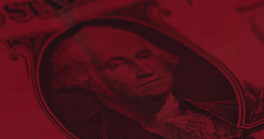 The camera slowly pulls into focus on the george washington portrait of a united states one dollar bill under a deep red light which highlights the intricate engraved lines of the banknote and the texture of the currency paper