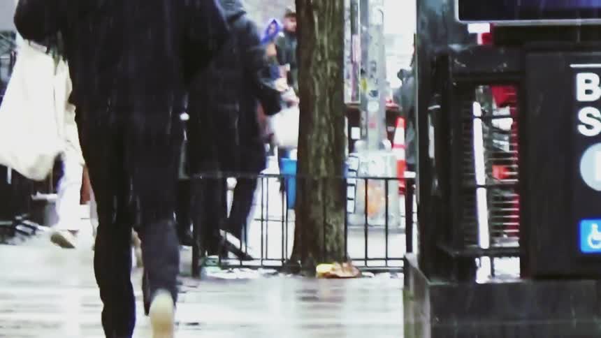 Pedestrians walking along a wet sidewalk on a rainy urban day