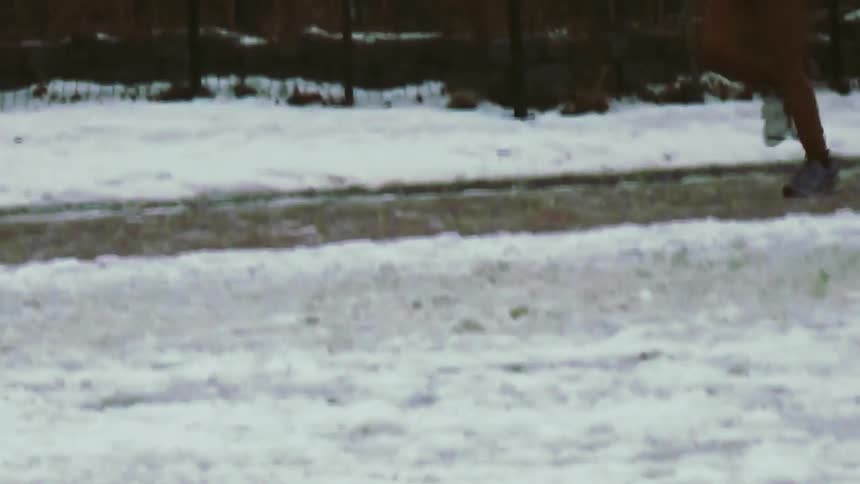 A person in red tights runs along an outdoor path on a snowy day with snow piled on both sides of the walkway