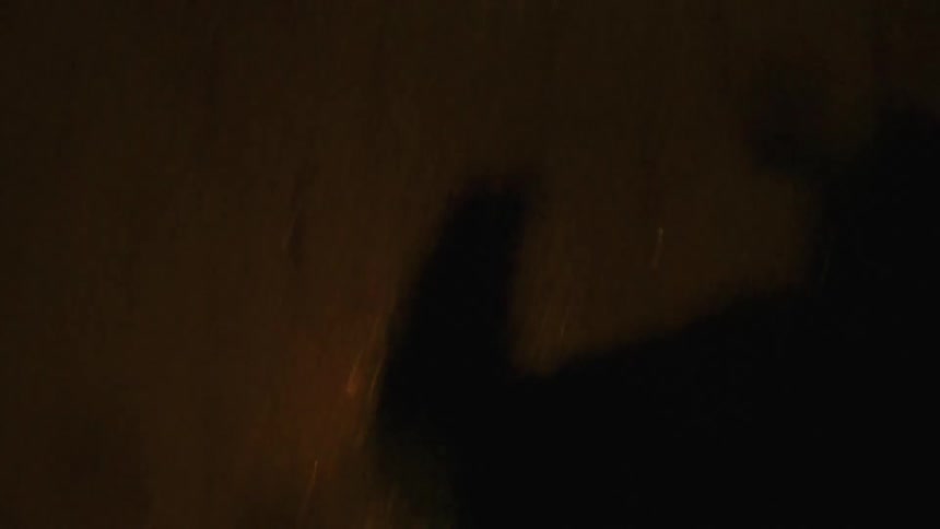 A firstperson perspective shows a person running or walking quickly across a dark surface with only their feet and legs occasionally visible in the dim lightthe scene is heavily shadowed and blurry featuring brief flashes of movement against a dark