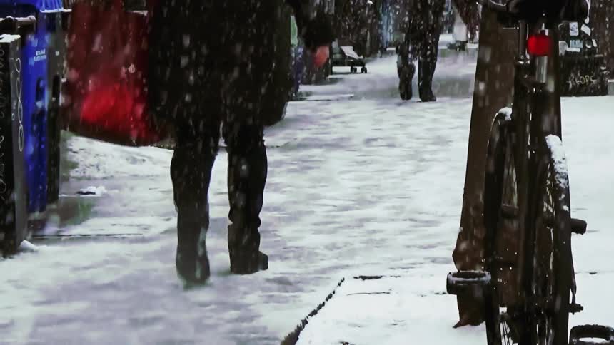 A group of people walking down a sidewalk covered in snow