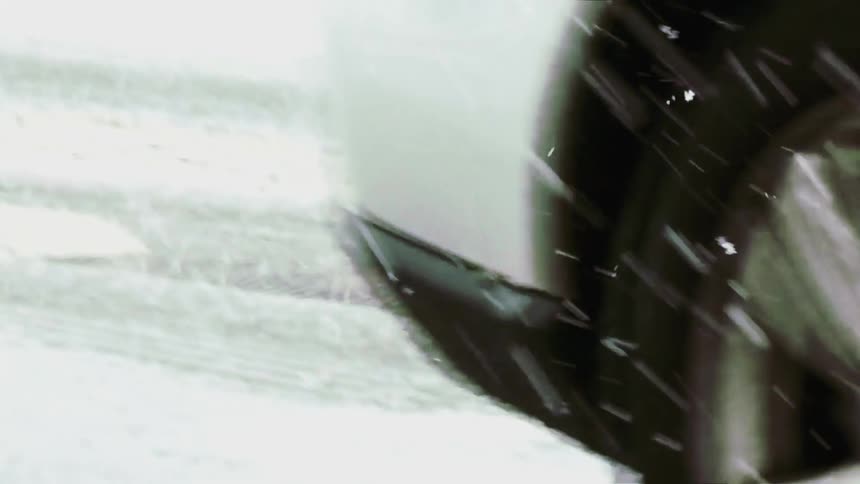 A close up of a white cars wheel driving through heavy snow and slush