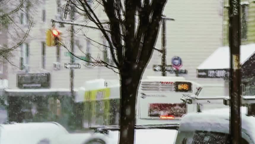 City bus traveling through a snowcovered intersection during snowfall