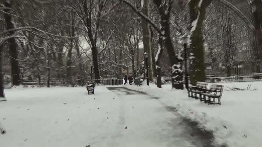 Some people walking around in a park covered in snow