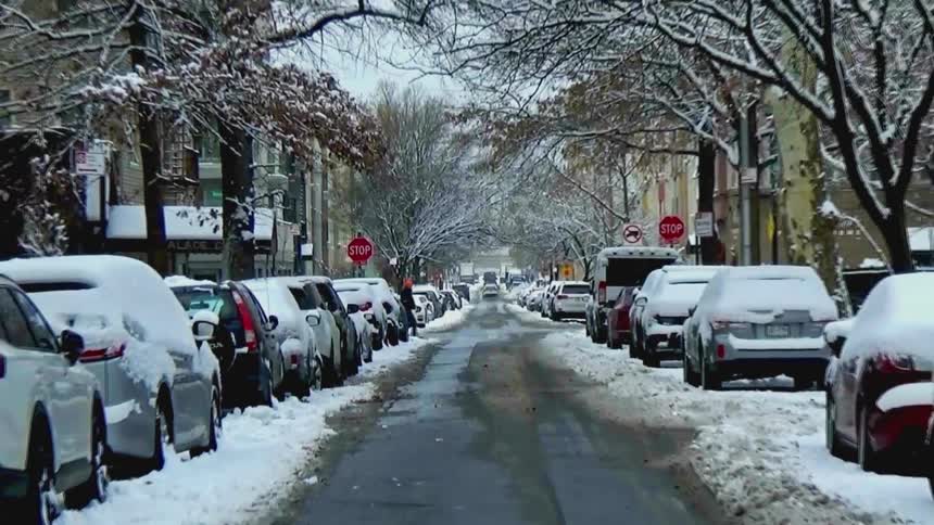 Residential street with parked cars covered in snow after snowfall