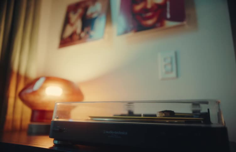 Turntable on a cabinet with a lit lamp and photographs on the wall