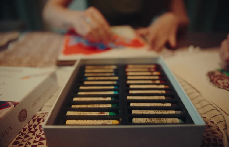 Person painting an illustration with colored pencils on a work table