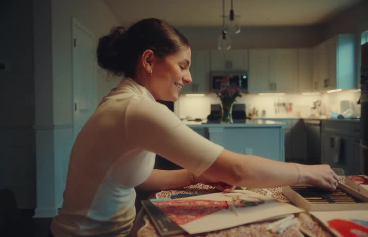 Woman arranges vinyl records on a table in a welllit residential kitchen