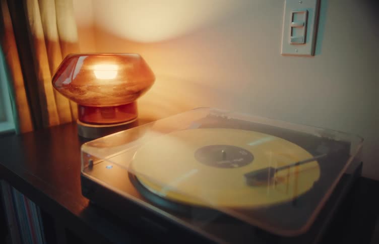 Pictures of people on a wall as a vinyl record plays on the turntable