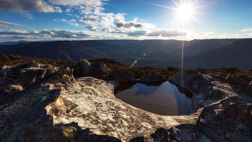 A pond at the peak of a mountain on a sunny day in the wilderness