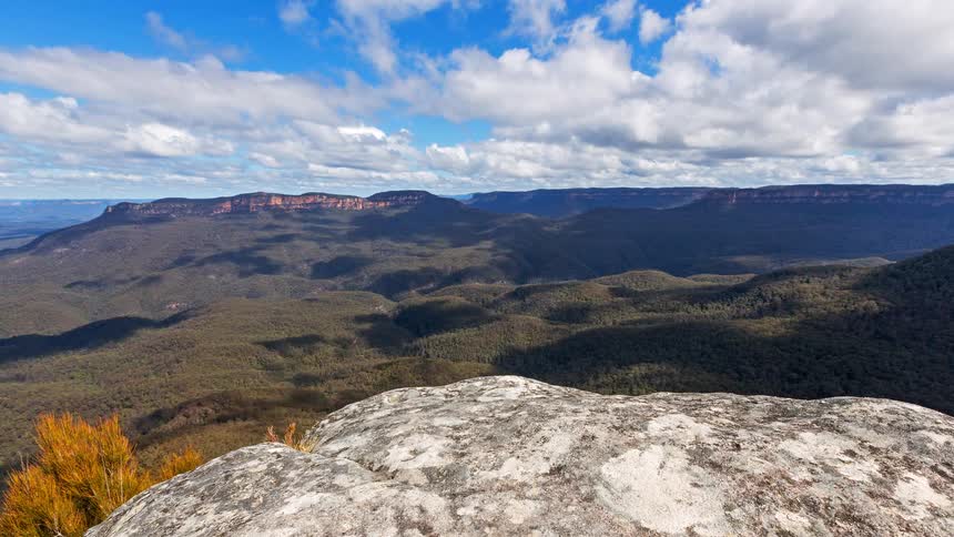 Wide view of forested mountains and valleys seen from rocky outcrop