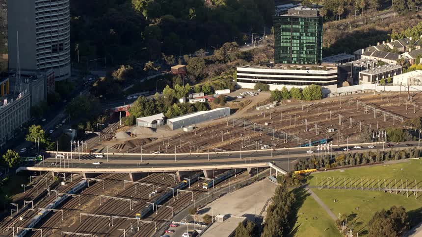 Aerial view of an urban overpass above railway lines with trains vehicle traffic and surrounding buildings
