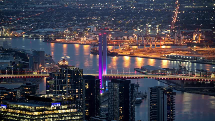 Time lapse of vehicles traveling across a bridge and through a city at night