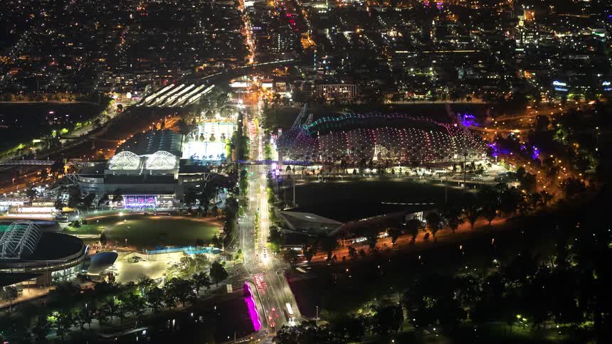 Illuminated sports complex at night within the urban grid seen from high altitude