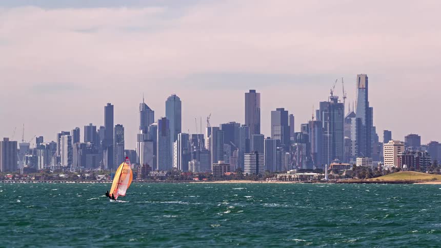 The small boat passes by the big city