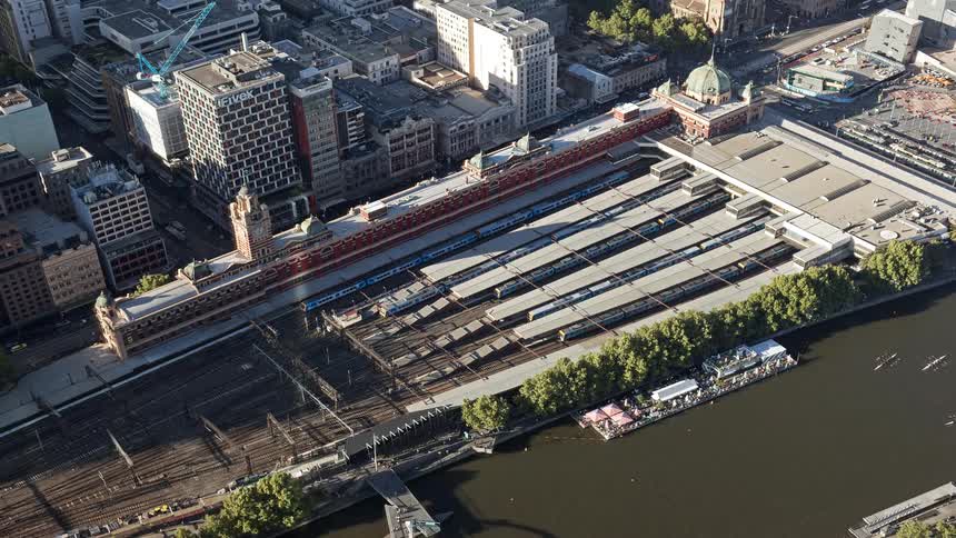 Trains moving past the city buildings on a winter day parallel the river