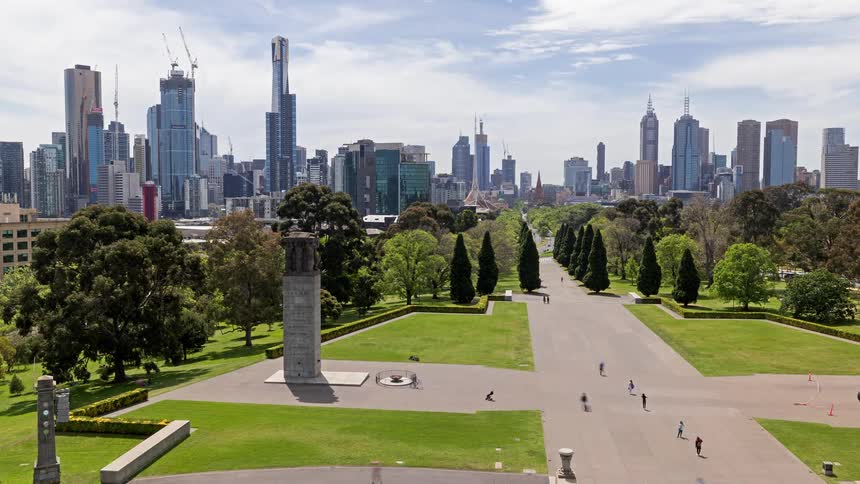 Groups of people walk around a park outside a metropolis