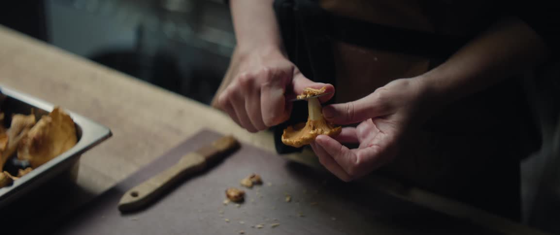 The cook is cutting a mushroom