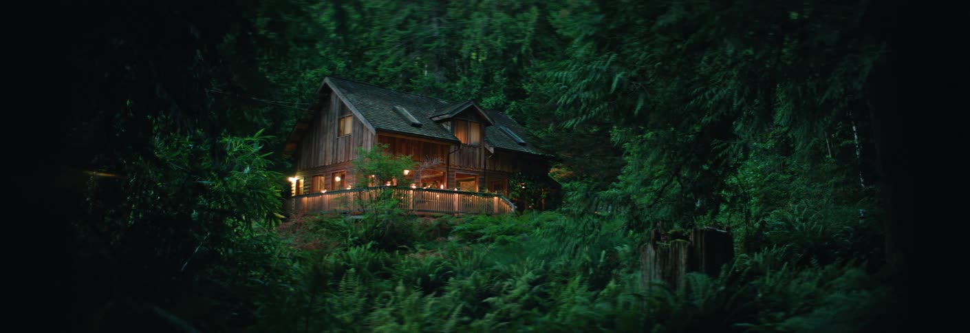 Cabin with lights on amid dense forest