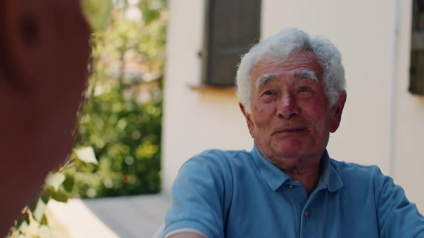 Whitehaired man chatting outdoors on a sunny day