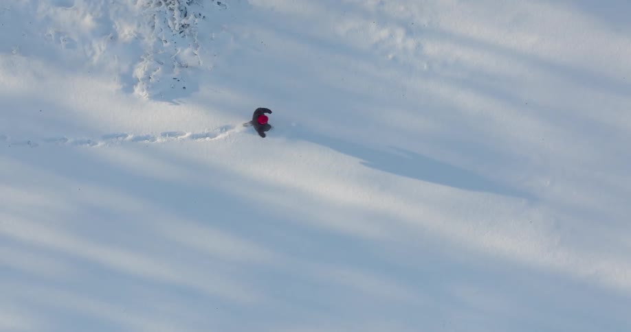 A person treks through deep snow leaving a trail of footprints