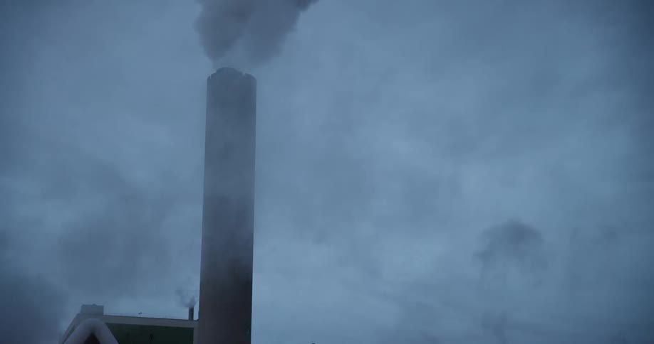 Smoke rises from a tall industrial chimney