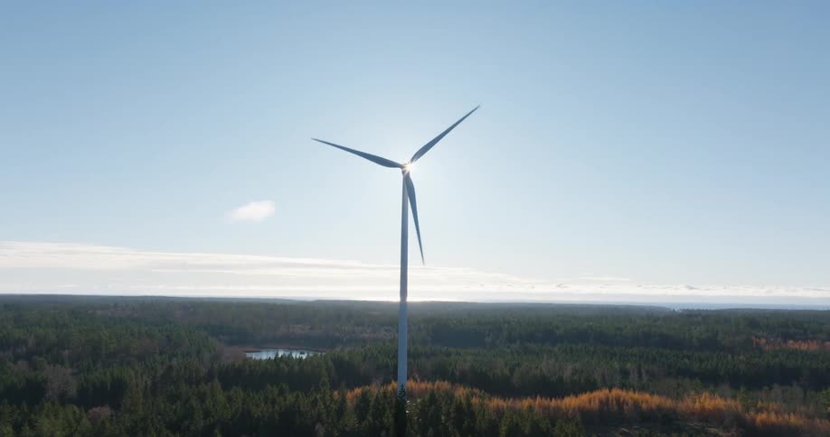 Wind turbine in operation in the middle of a valley with forest