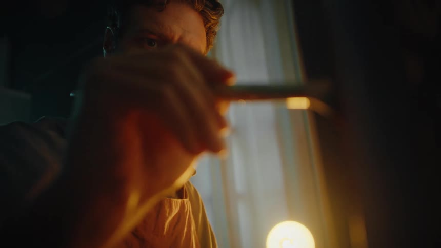 Man paints with a brush under warm lighting in an indoor setting