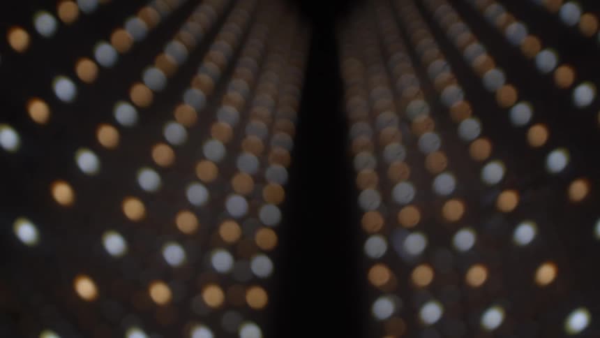 Outoffocus light points arranged in symmetrical rows converging toward the center in deep perspective
