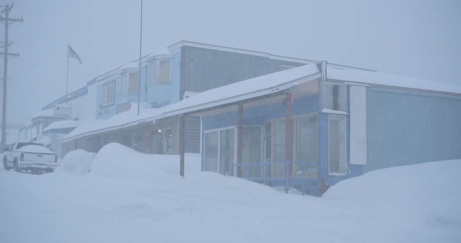 Snow falls onto buildings and streets already covered by snow on a winter day