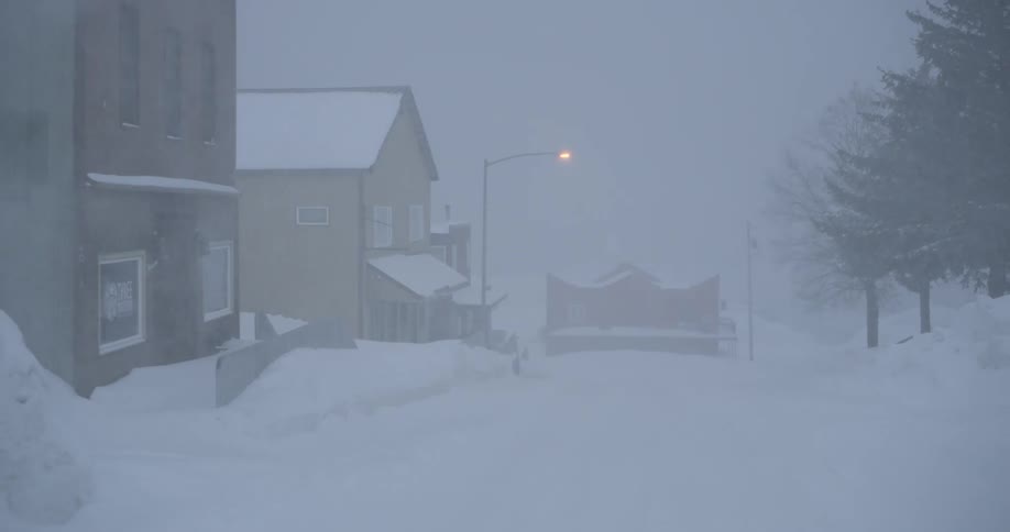 Heavy snow is falling on a town in the evening