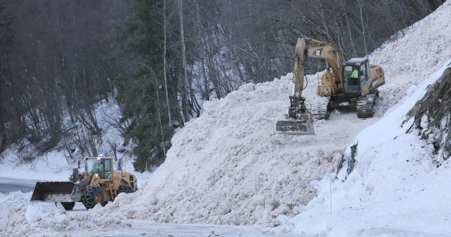 Trucks clearing snow from an avalanche on a mountain road