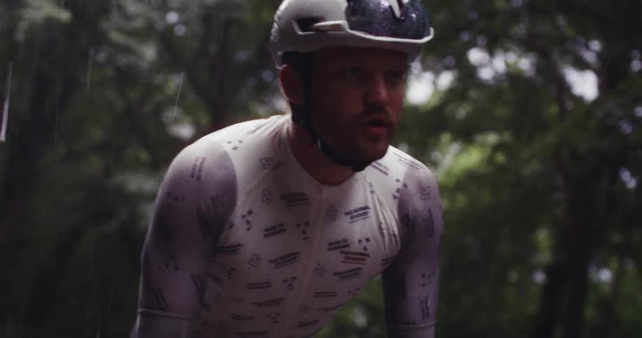 Man wearing a helmet rides his bicycle in the rain