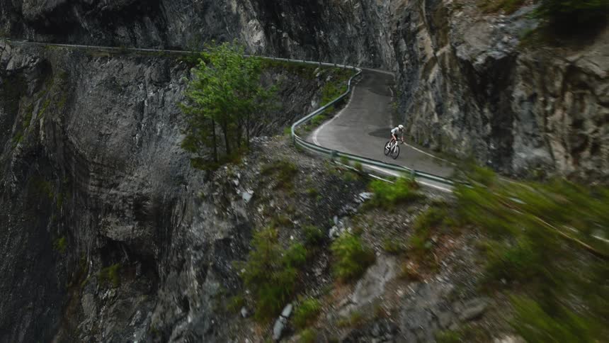 The man is cycling on the cliff