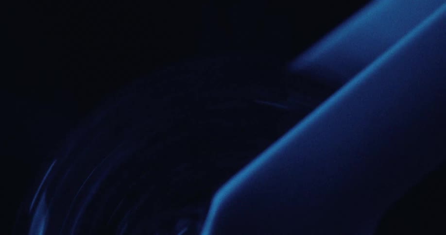 A close view of a blue wheel or circular object spinning rapidly in a dark and moody setting