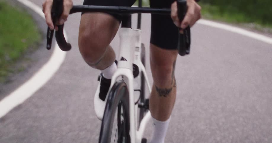 A focused cyclist in a green jersey pedals intensely along a road